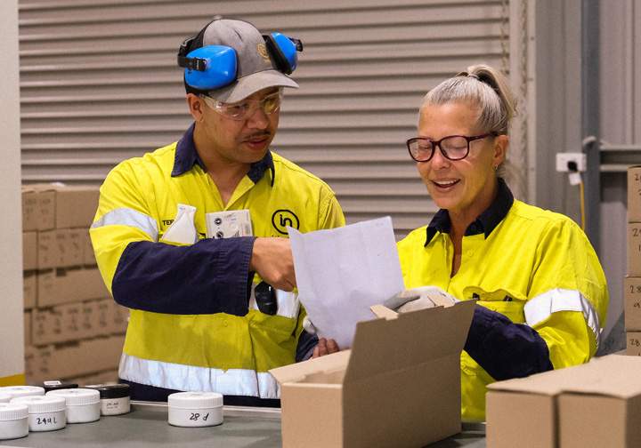 A man and a woman sort through tested gold samples in a laboratory. 