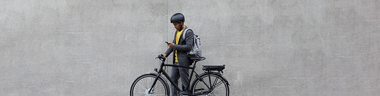 A man with his electric bicycle standing in front of a concrete wall