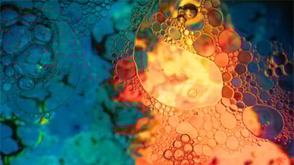 En makrobild på en emulsion av olja och vatten under starkt blått och orangt ljus